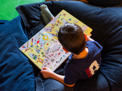 Un enfant lit un livre pendant les Vacances à Orsay. 